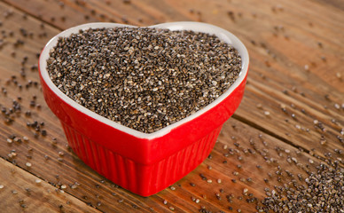 chia seeds in a heart shaped bowl on  rustic wooden table.