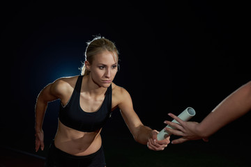 athletic runners passing baton in relay race