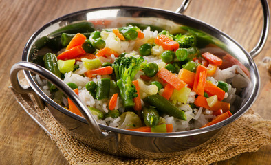 Rice with vegetables on a  rustic wooden table.