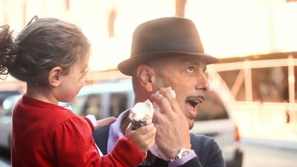 A happy little girl kisses her dad's cheek after eating some ice-cream