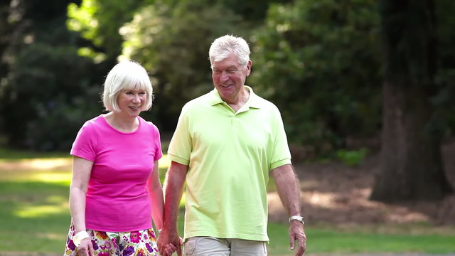 Happy senior couple hold hands and walk together. Medium shot.