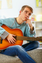 Young man playing guitar at his home