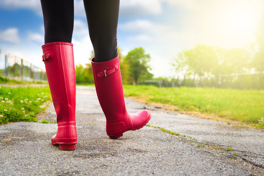 Young woman in pink rain boots walking. detail of boots.