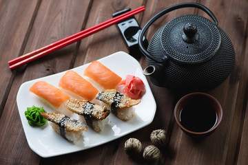 Obrazy na Szkle  Zestaw sushi z pałeczkami i herbatą na ciemnym drewnianym tle