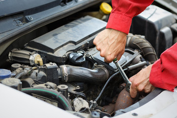 Worker in red overalls working  on car car engine