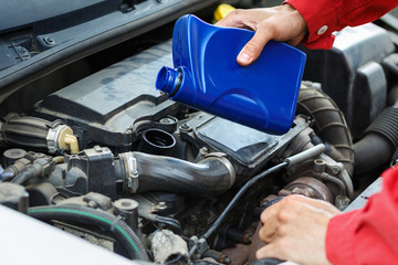 Worker in red overalls checking the oil on car car engine