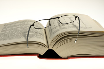 dickes aufgeschlagenes Buch mit Brille