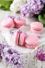 French pink macarons with lilac flowers on white wooden backgrou