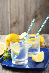 Fresh lemonade with lemon on grey wooden background