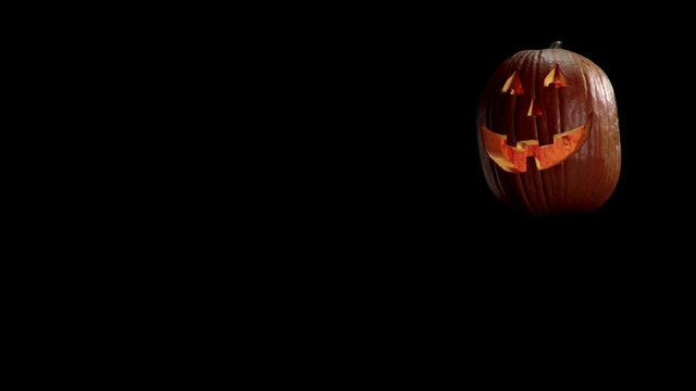 A Jack-o-lantern with a smiling face flickers on a black background