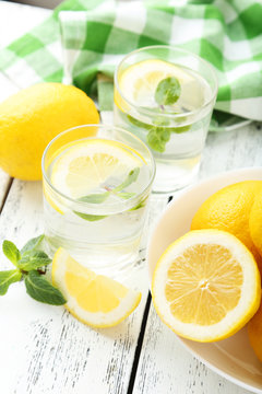 Fresh lemonade with lemon on white wooden background