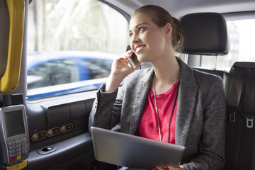 Businesswoman working while drive a taxi