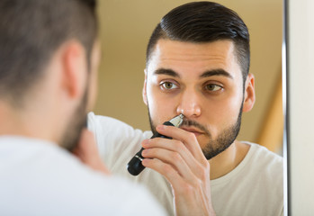 Young man using hair trimmer.