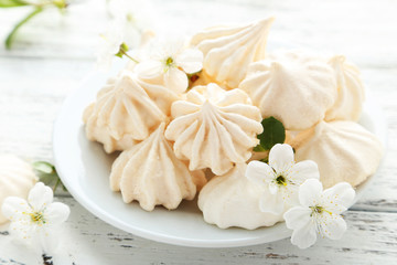 Fototapeta na wymiar French meringue cookies on plate on white wooden background