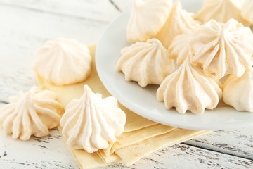 French meringue cookies on plate on white wooden background