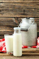 Can and glass of milk on brown wooden background