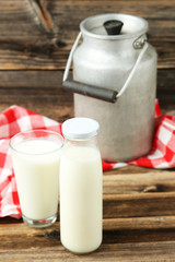 Can and glass of milk on brown wooden background