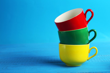 Colorful cups on blue wooden background