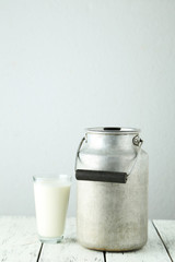 Can and glass of milk on white wooden background