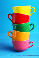 Colorful cups on blue wooden background