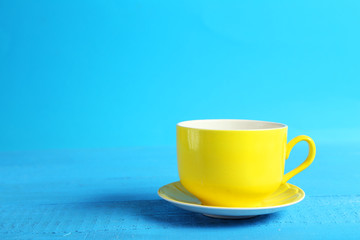 Yellow cup on blue wooden background