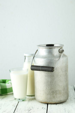Can and glass of milk on white wooden background