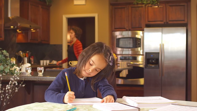 A little girl does her homework on the dinning room table