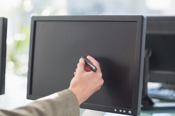 Businesswoman touching computer screen with pen 