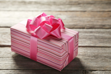 Gift box with pink bow on grey wooden background