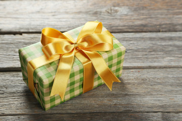 Gift box with golden bow on grey wooden background