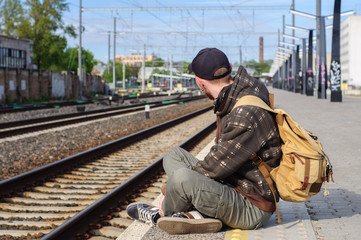 Fototapeta premium Young man waits train on railway station