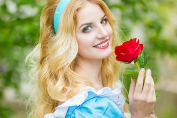 Portrait of a beautiful young blonde woman with long hair dressed as Alice in Wonderland.The girl...