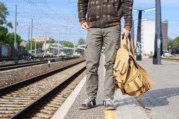 Young man waits train on railway station