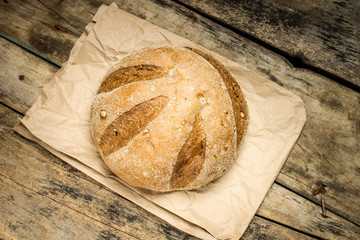 Loaf of fresh baked wheat bread on wood background