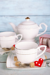 Woman pouring hot tea from teapot into cup wooden background