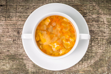 Fish soup in white bowl on wood background