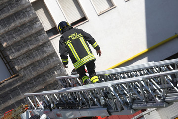 firefighter walking on extended ladder of firetrucks during the