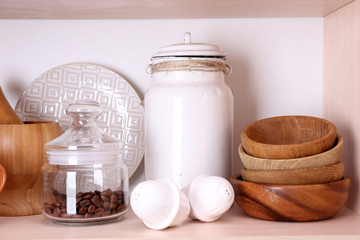 Kitchen utensils and tableware on wooden shelf