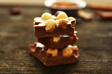 Stack of chocolate with nuts on wooden table, closeup