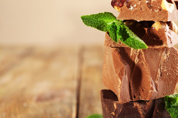 Stack of chocolate with nuts on wooden table, closeup