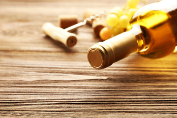 Fototapeta na wymiar Glass bottle of wine with corks, corkscrew and grapes on wooden table background