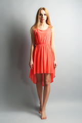 Expressive young model in orange dress on gray background