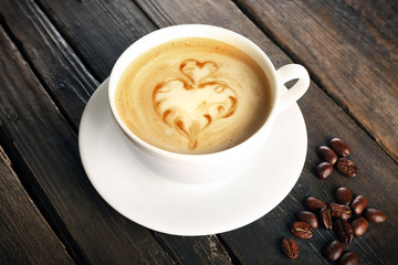 Cup of coffee latte art with grains on wooden background