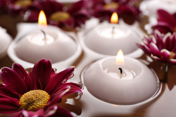 Obraz na płótnie Canvas Bowl of spa water with flowers and candles, closeup