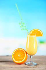 Glass of summer cocktail on wooden table on bright blurred background