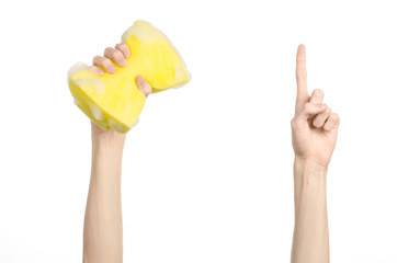 Hand holding a yellow sponge wet with foam isolated studio