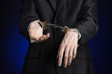 businessman in a black suit with handcuffs on his hands studio