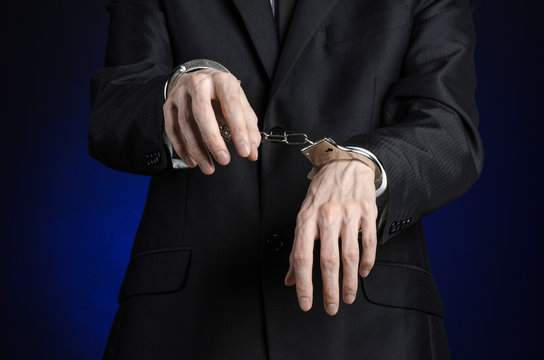 businessman in a black suit with handcuffs on his hands studio