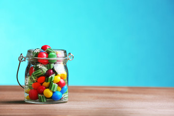 Obraz premium Colorful candies in jar on table on blue background
