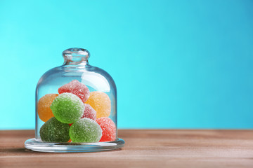 Colorful candies in jar on table on blue background